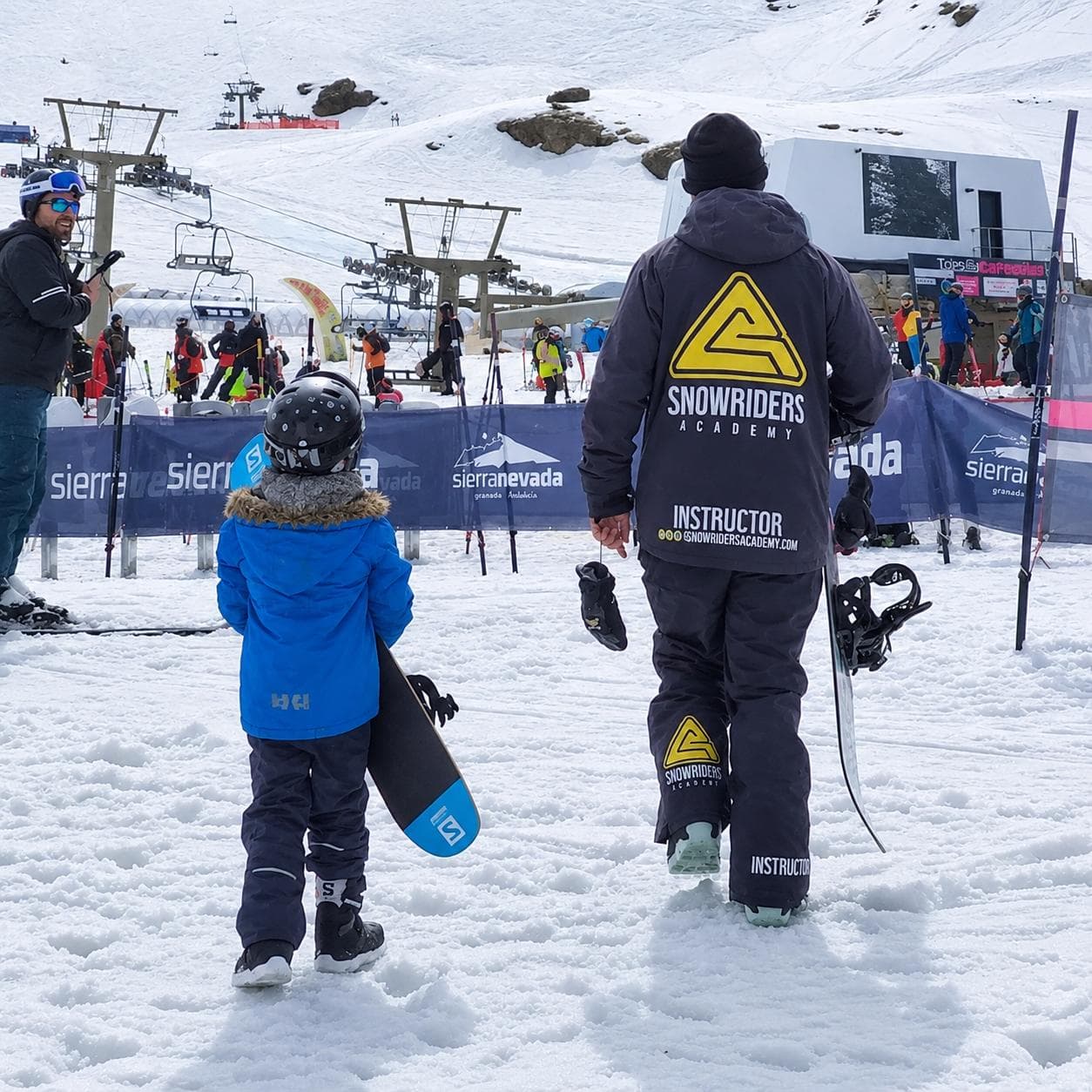 Monitor de Snow Riders Academy caminando con un niño hacia la pista