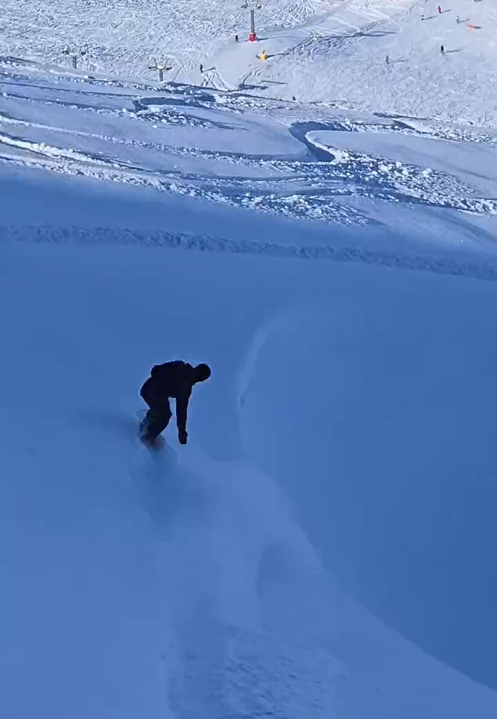 Snowboarder levantando una nube de nieve polvo en Sierra Nevada